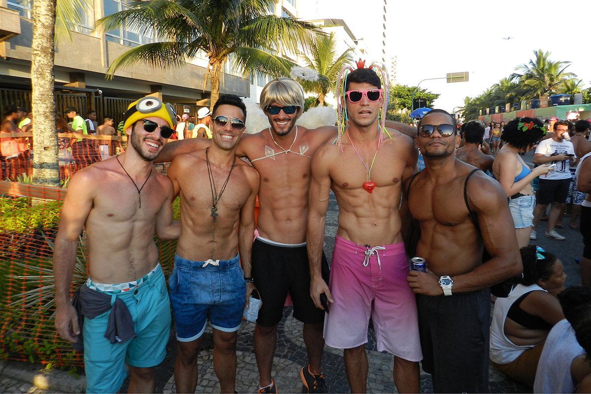 Group of young men wearing Carnaval accessories and celebrating street festivities. The six-pack abs are not part of the costume.